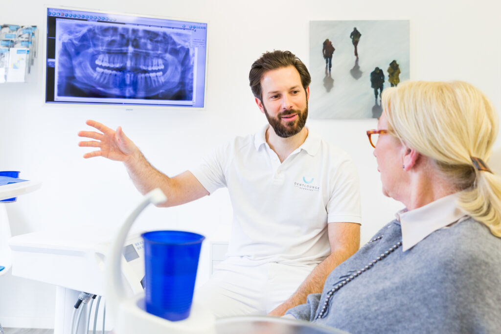 Herr Dr. Hetheier erklärt einer Patientin das Feste-Zähne-an-einem-Tag Konzept.