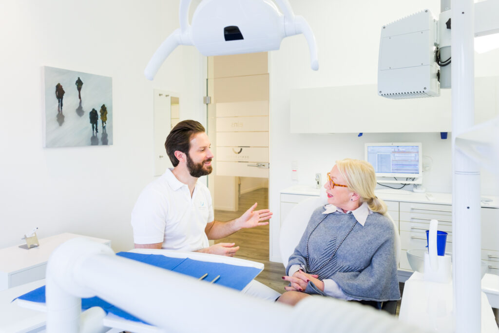 Herr Dr. Hetheier erklärt einer Patientin das Feste-Zähne-an-einem-Tag Konzept.