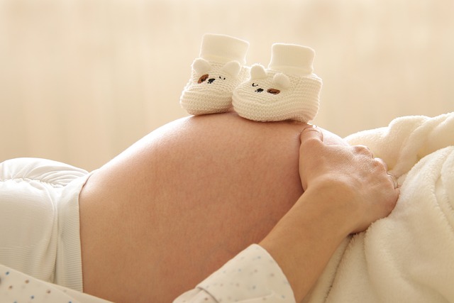 Schwangere Frau mit Babyschuhen auf dem Bauch